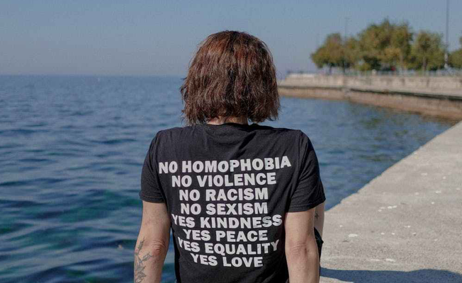 Person sitting by water with message t-shirt