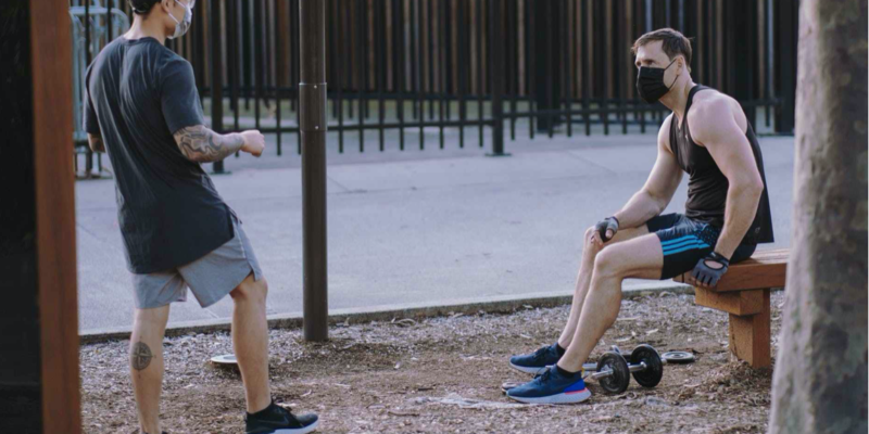 two guys in a park with workout equipment and face masks