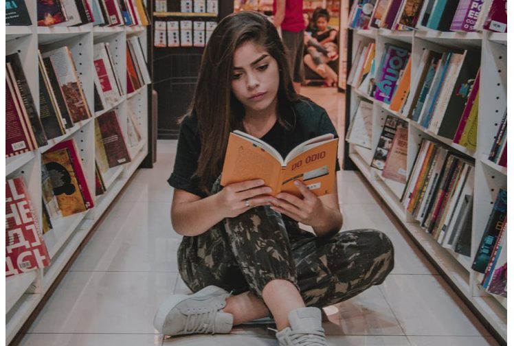 girl reading in library courtesy Nicole Berro on Pexels.com
